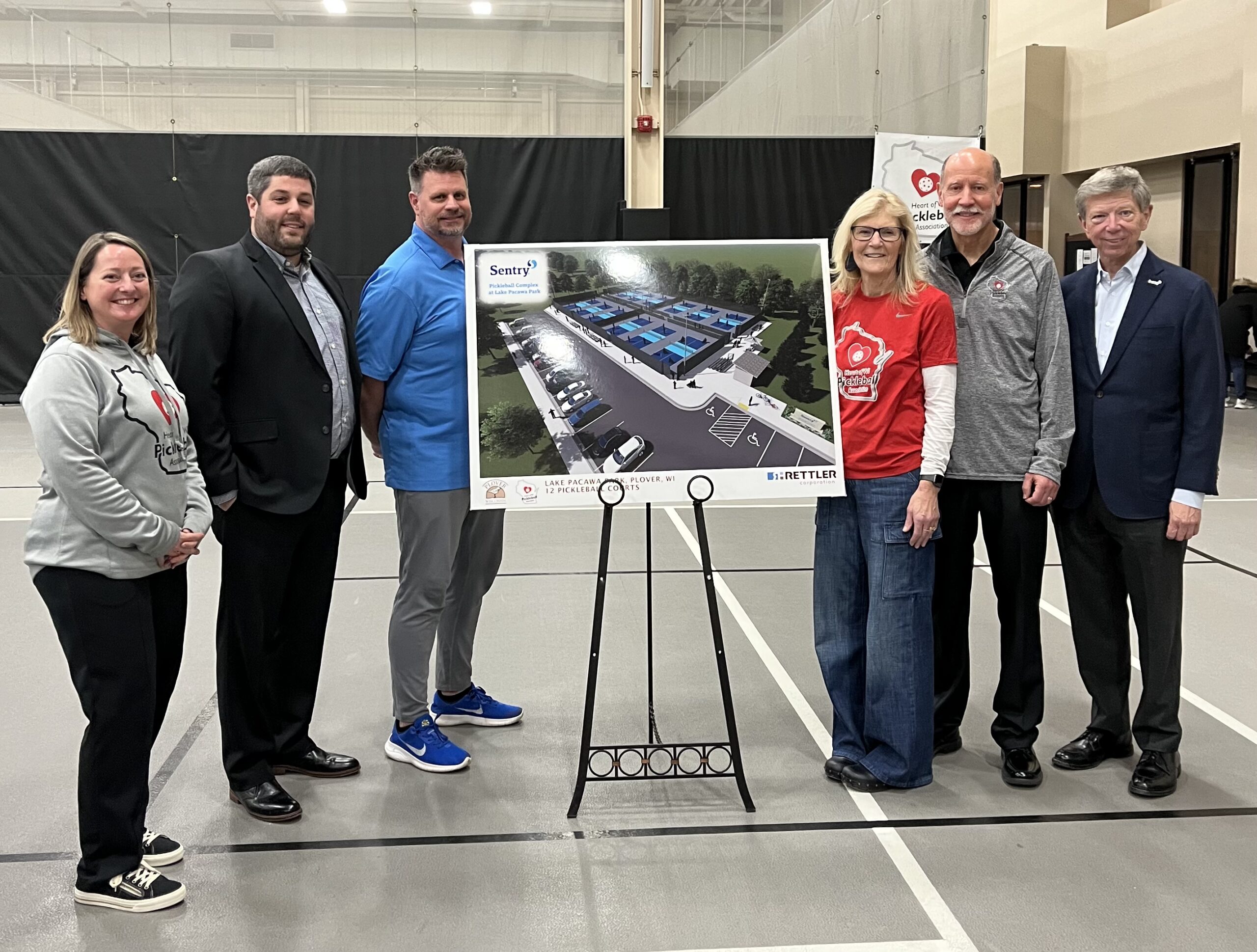 Organizers pose with rendering of Sentry Pickleball Complex